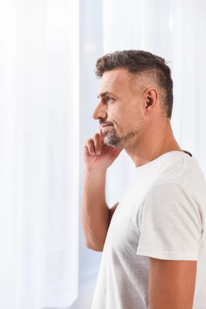 profile of handsome man standing near window utc